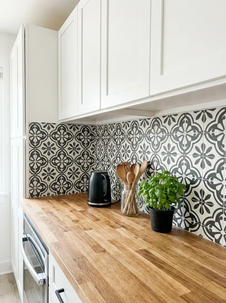  kitchen backsplash covered in matte black and white cement tile style peel and stick tiles with a geometric floral pattern